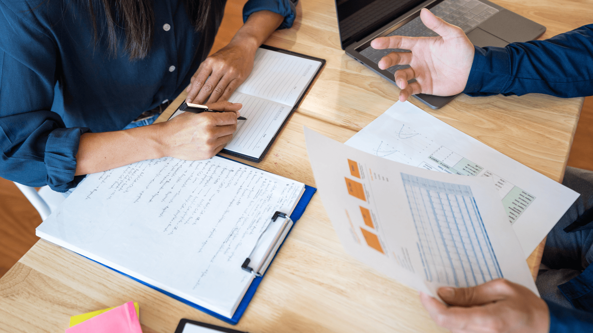 Two people are discussing the graph and a laptop on the table