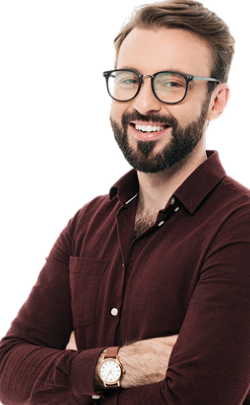 A smiling man with short brown hair and a neatly trimmed beard wearing glasses and a maroon button-up shirt, standing with his arms crossed against a black background.