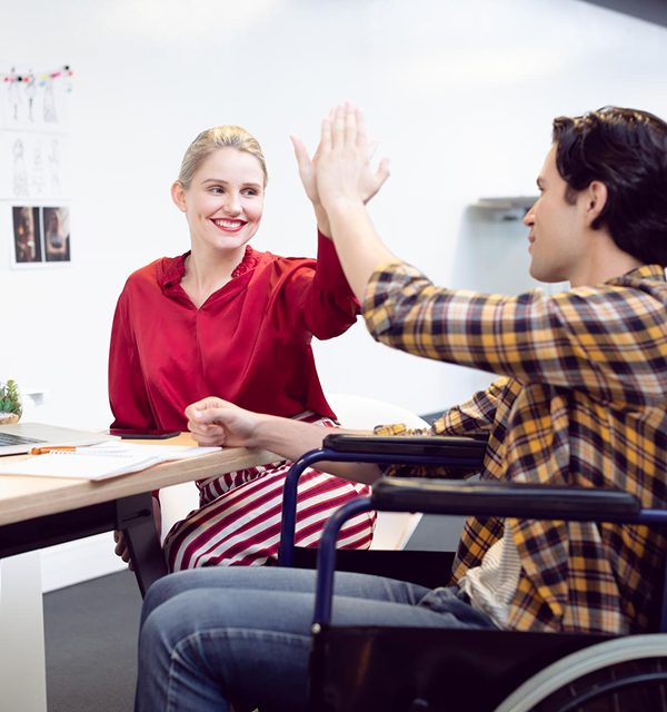 a woman smiling at the man sitting in the wheelchair, and clapping their hands